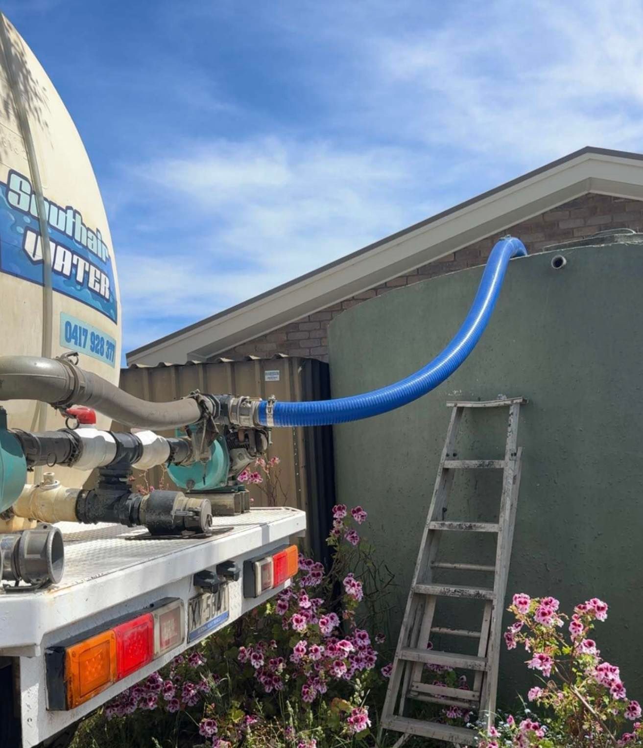 A Water Truck is Connected to a Large, Green Residential Water Tank — SOUTHAIR WATER In Mornington, TAS