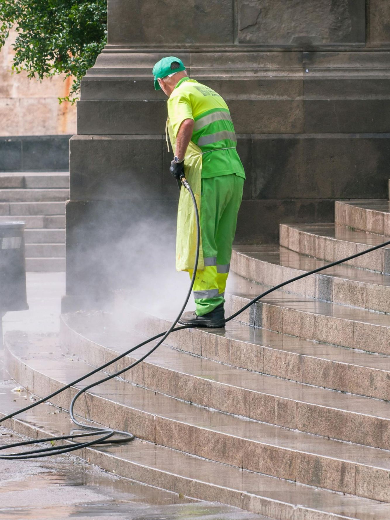 A man is cleaning the steps of a building with a high pressure washer.