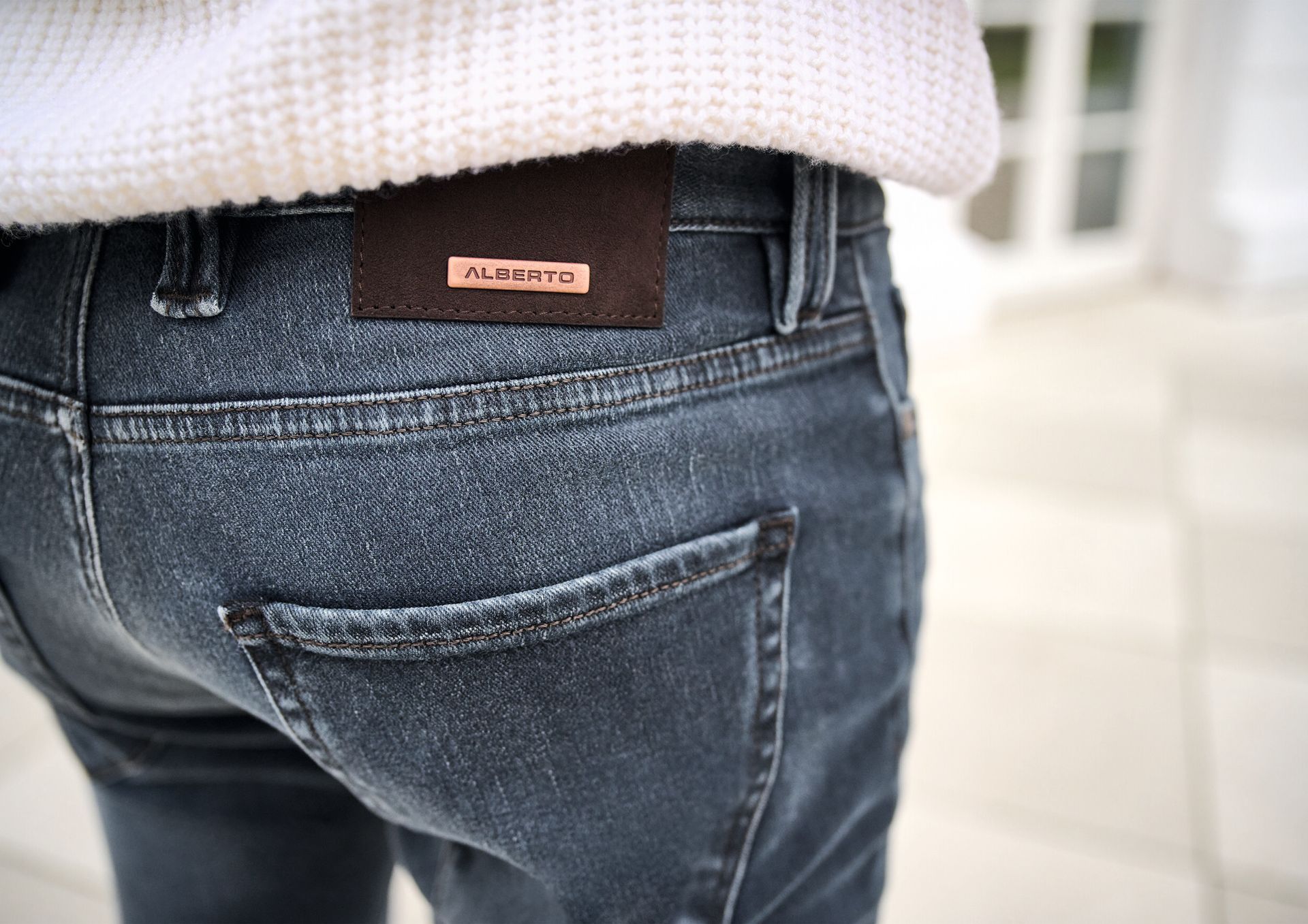 Dark blue jeans with a brown label on the back, person wearing a white sweater.