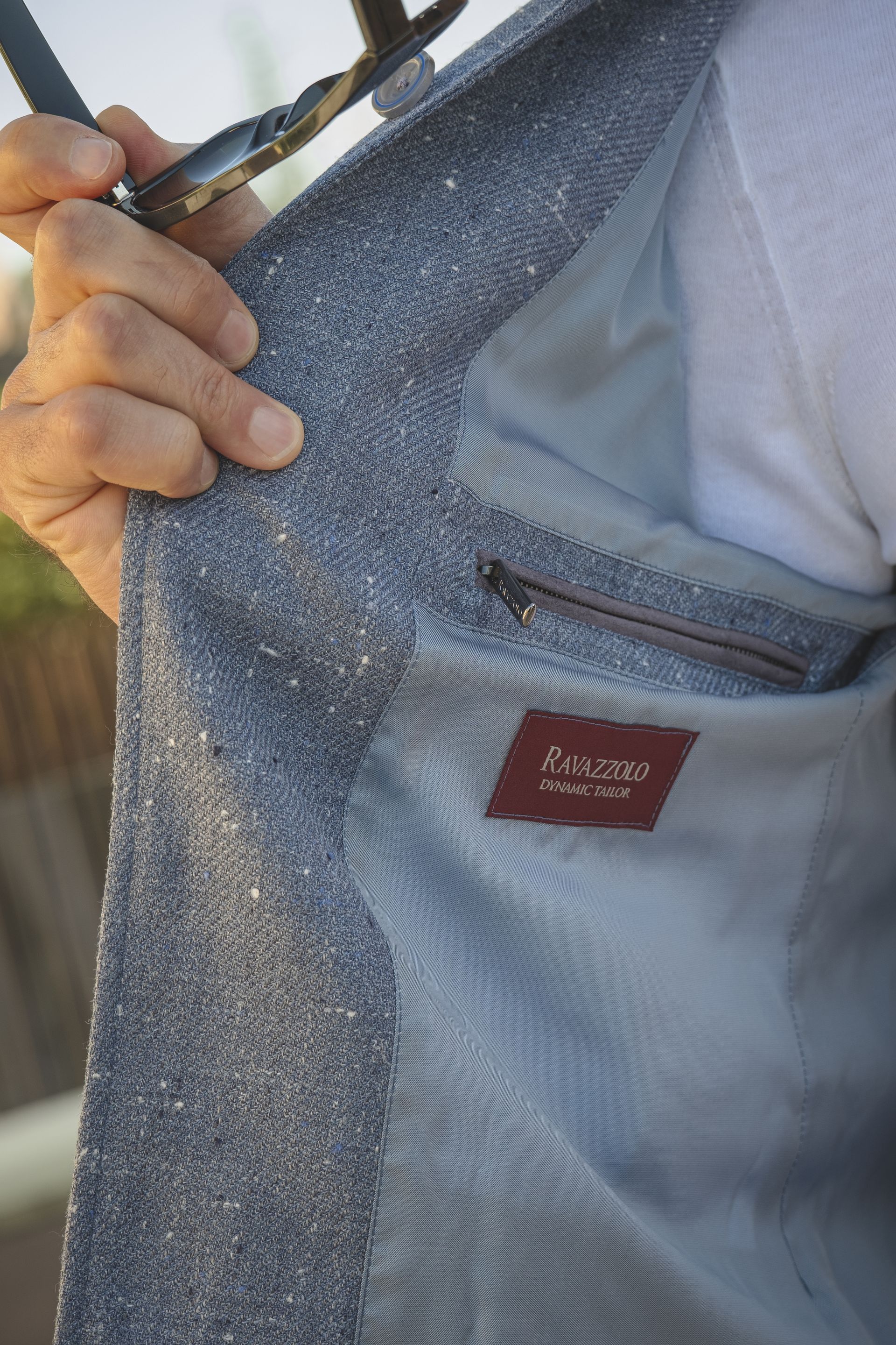 Person holding open blue blazer, showing lining, inside pocket, and brand tag.