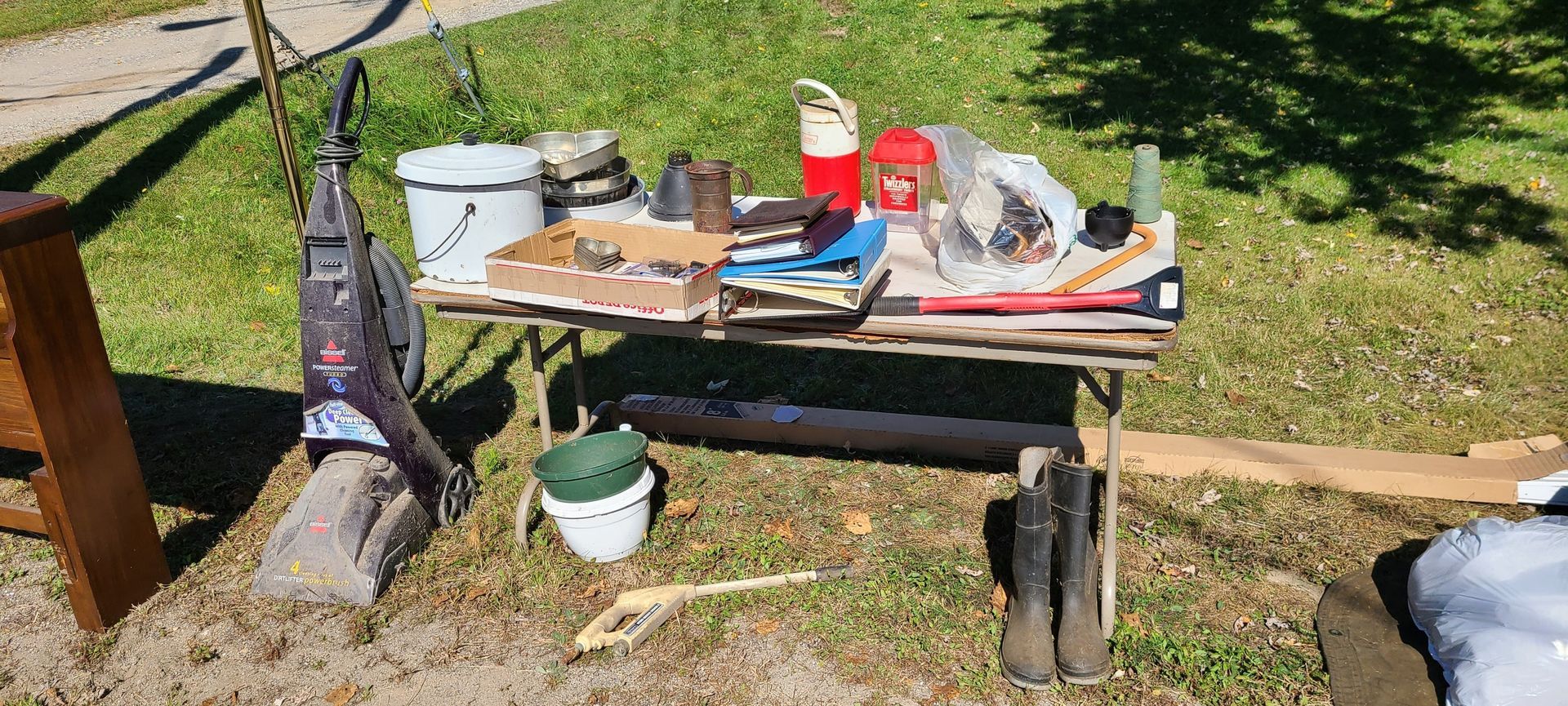 Backyard workbench with tools, buckets, and a hanging bag in the sun near a wooden fence