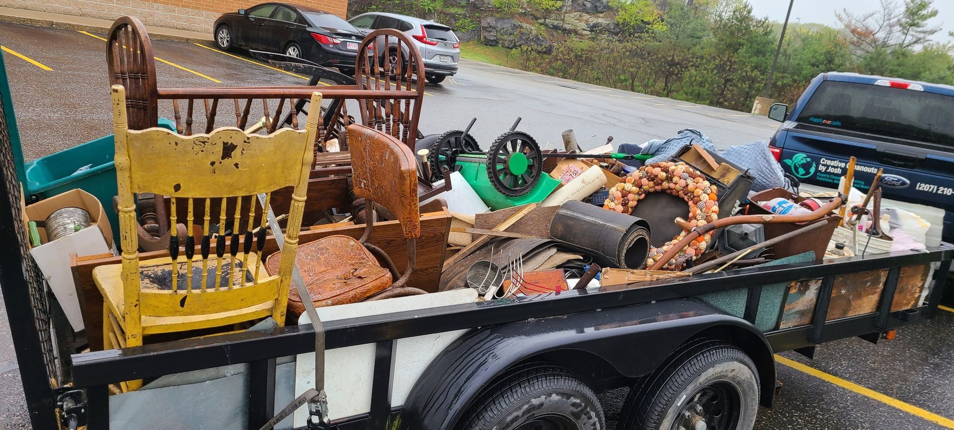 Trailer loaded with furniture and assorted debris in a parking lot