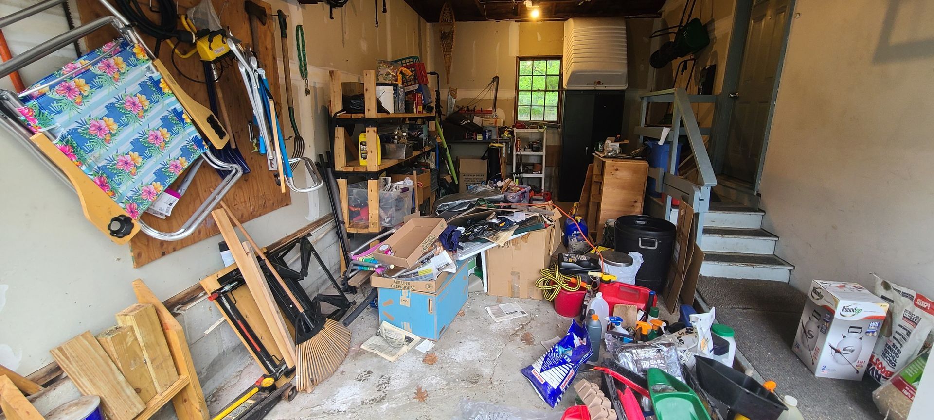 Cluttered garage or shed with scattered tools, boxes, and household items in disarray