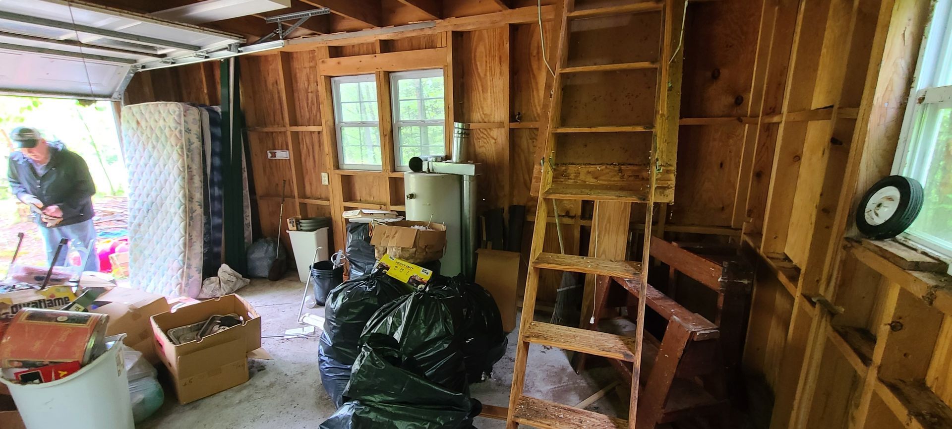 Partially renovated room with exposed studs, scattered tools, and a window by the doorway