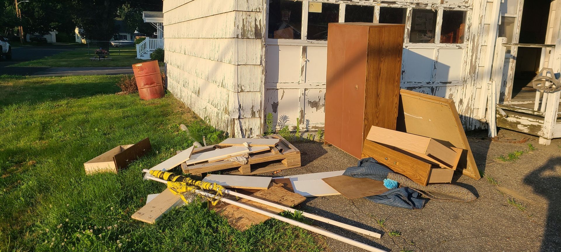 Pile of construction debris and broken wood outside a small shed in a yard.