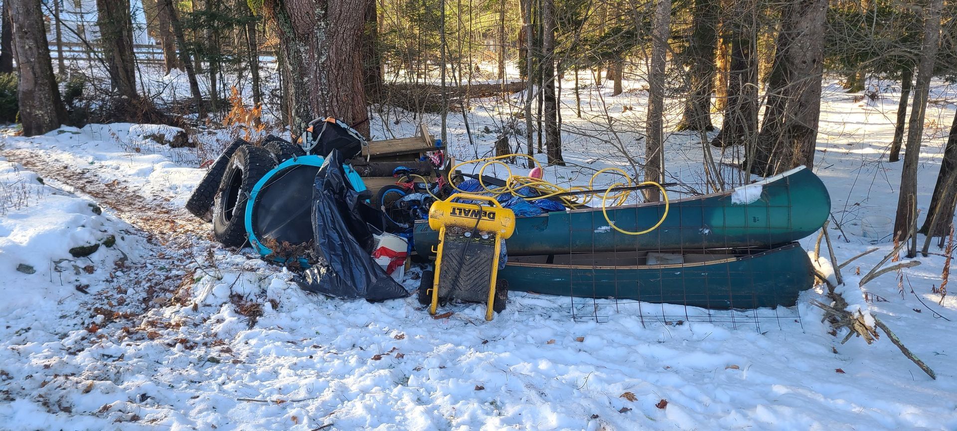 Snow-covered canoe or kayak with gear in a wooded winter setting