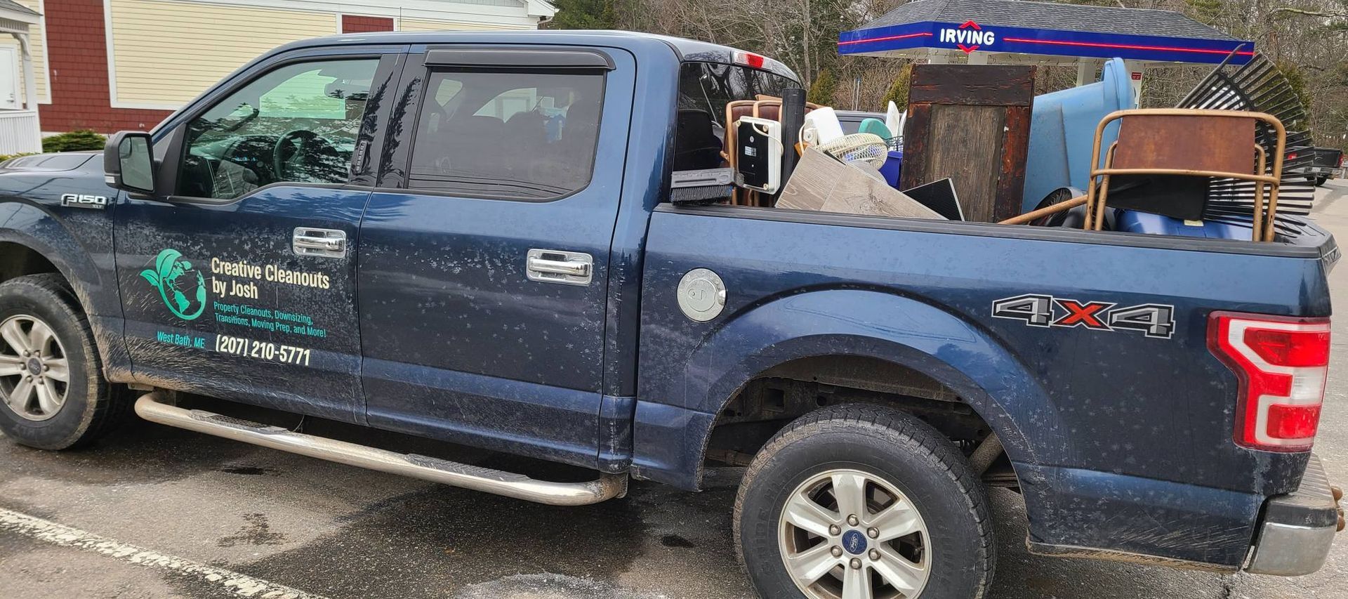 Blue pickup truck with business decals parked outdoors, carrying equipment in the bed