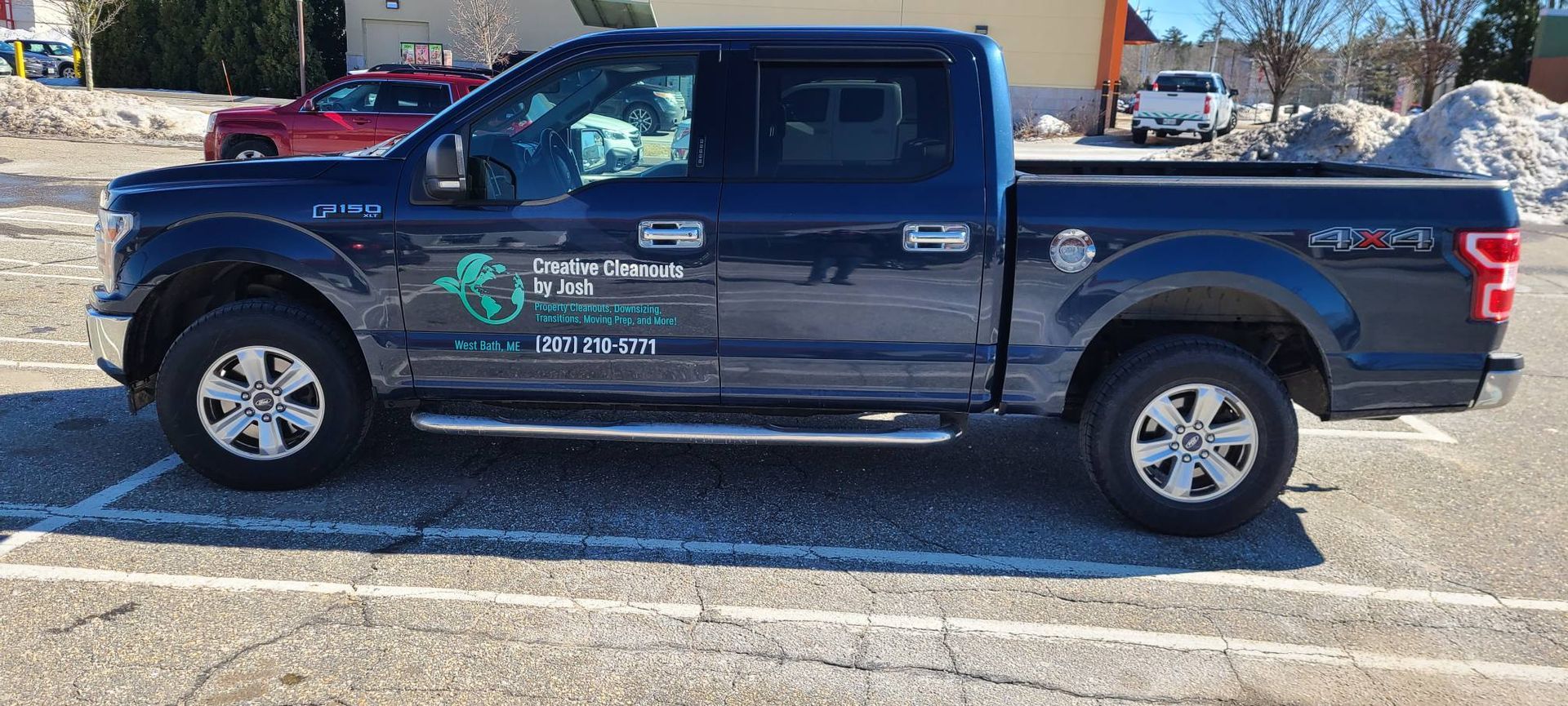 Blue pickup truck parked in a lot with company decals on the driver’s door