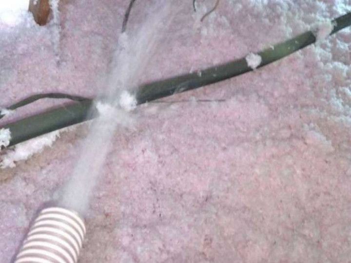 A Hose is Being Used to Blow Insulation Into a Room
