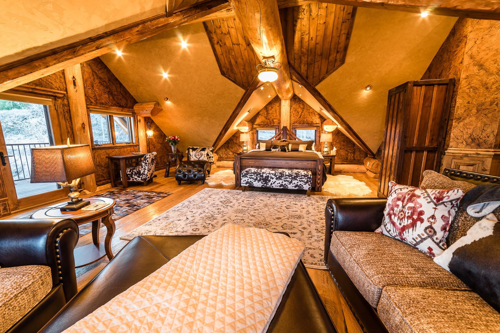 Cozy wood-paneled cabin living room with vaulted ceiling, sofas, rug, and warm lighting