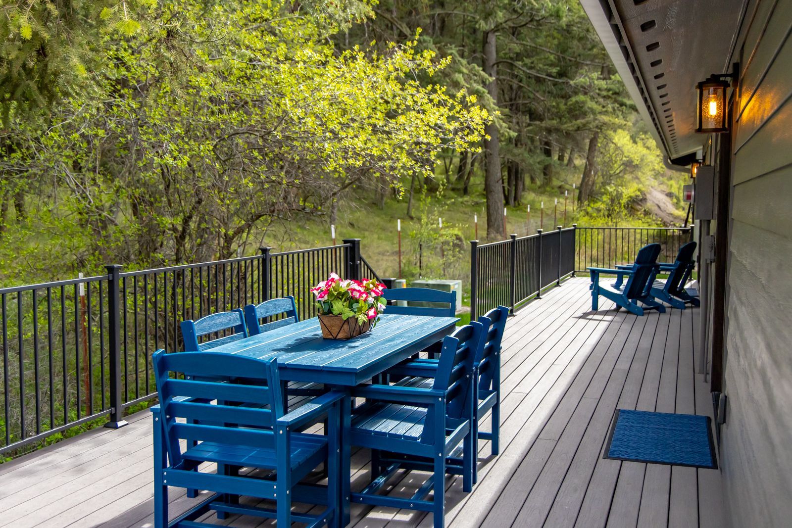 Blue patio table and chairs on a wooden deck overlooking a wooded hillside