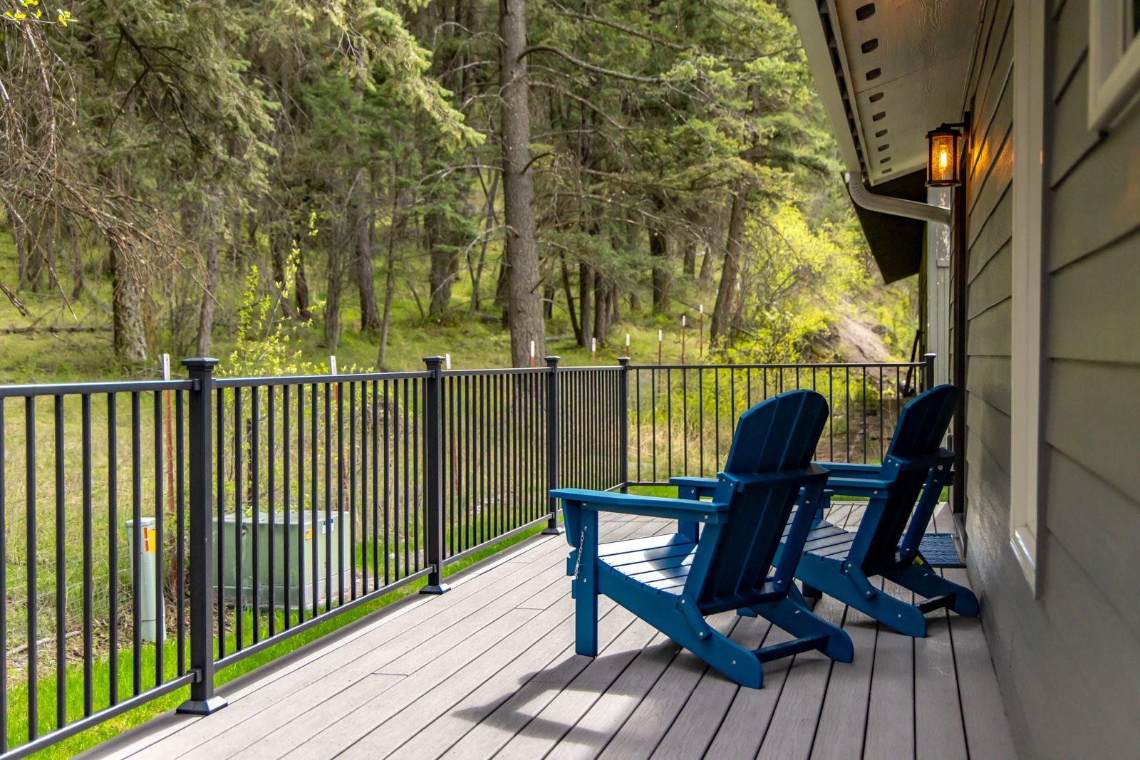 Covered porch with blue chairs overlooking a wooded yard