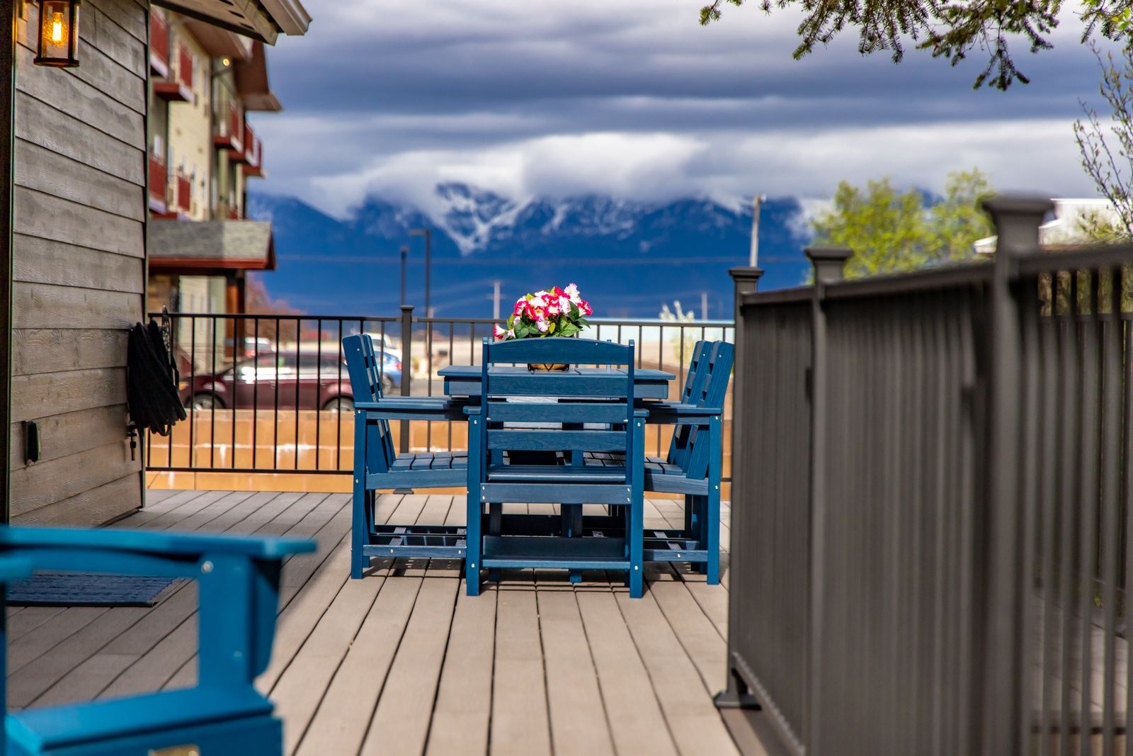 Patio deck with blue table and chairs overlooking a lake and mountains under cloudy skies