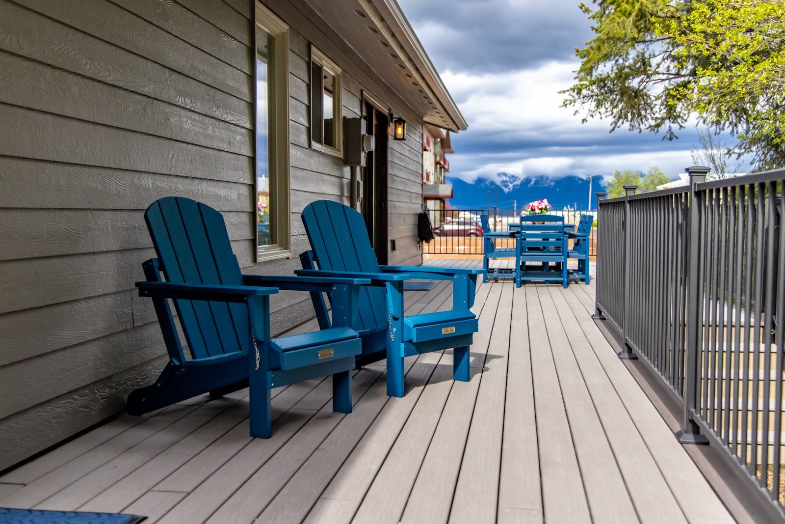 Wooden deck with blue chairs beside a house, overlooking water and distant mountains