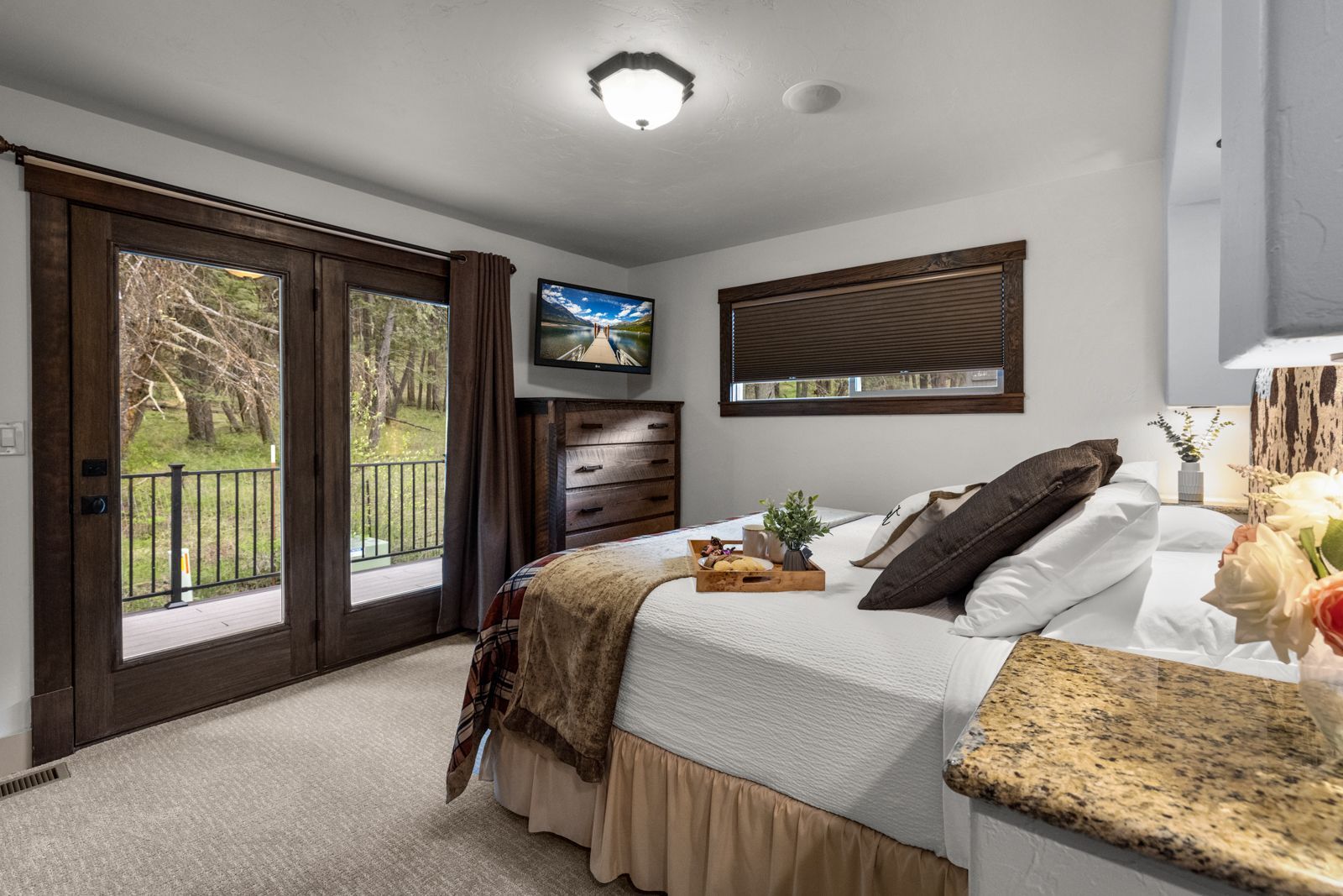 Bedroom with bed, dresser, wall TV, and glass doors opening to a balcony.