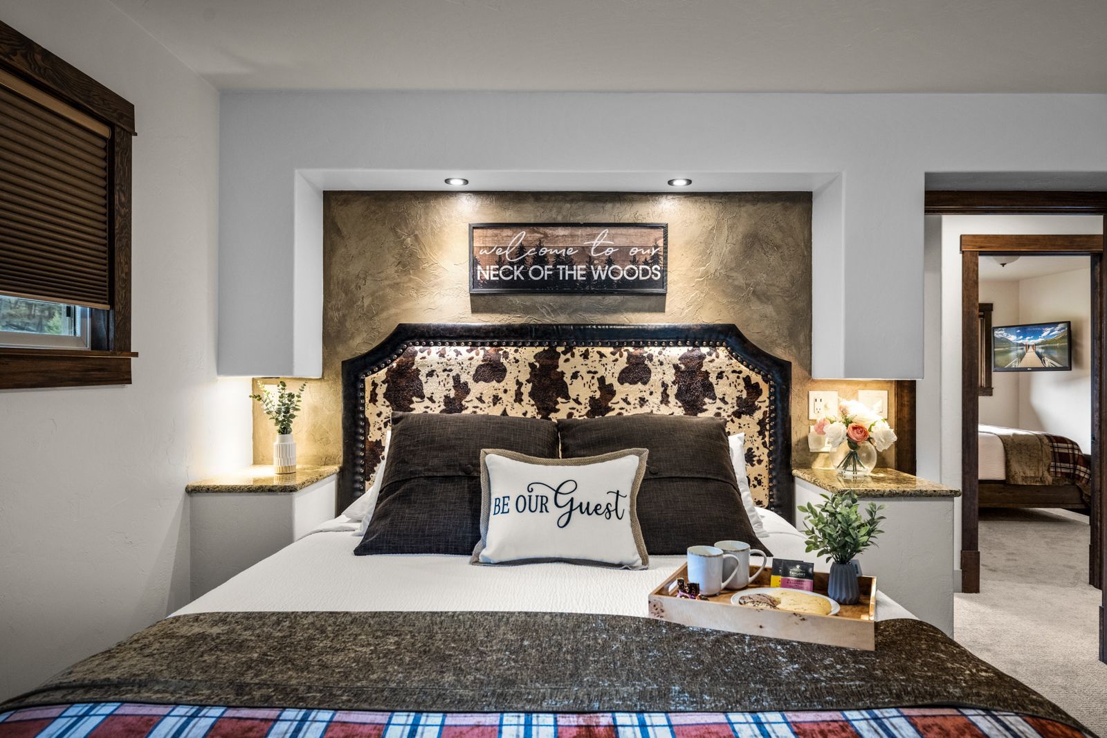 Cozy bedroom with patterned headboard, cream walls, bedside lamps, and a neatly made bed with decorative pillows