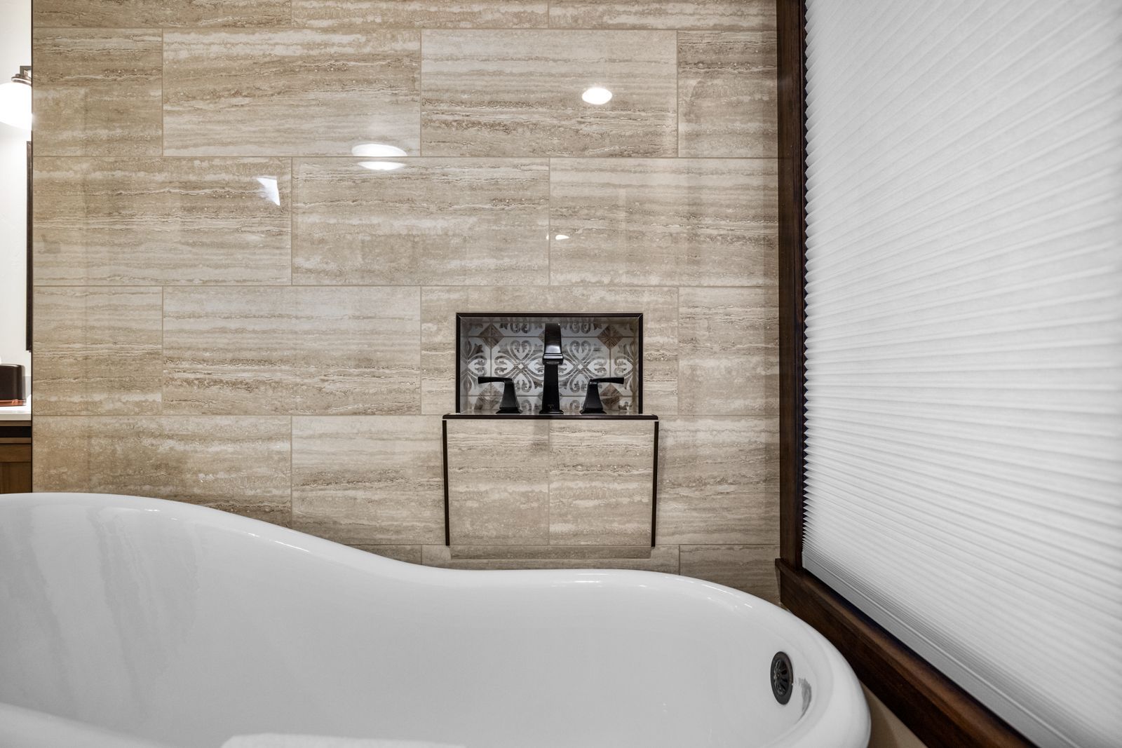 Modern bathroom with freestanding tub, stone accent wall, and wall-mounted faucet
