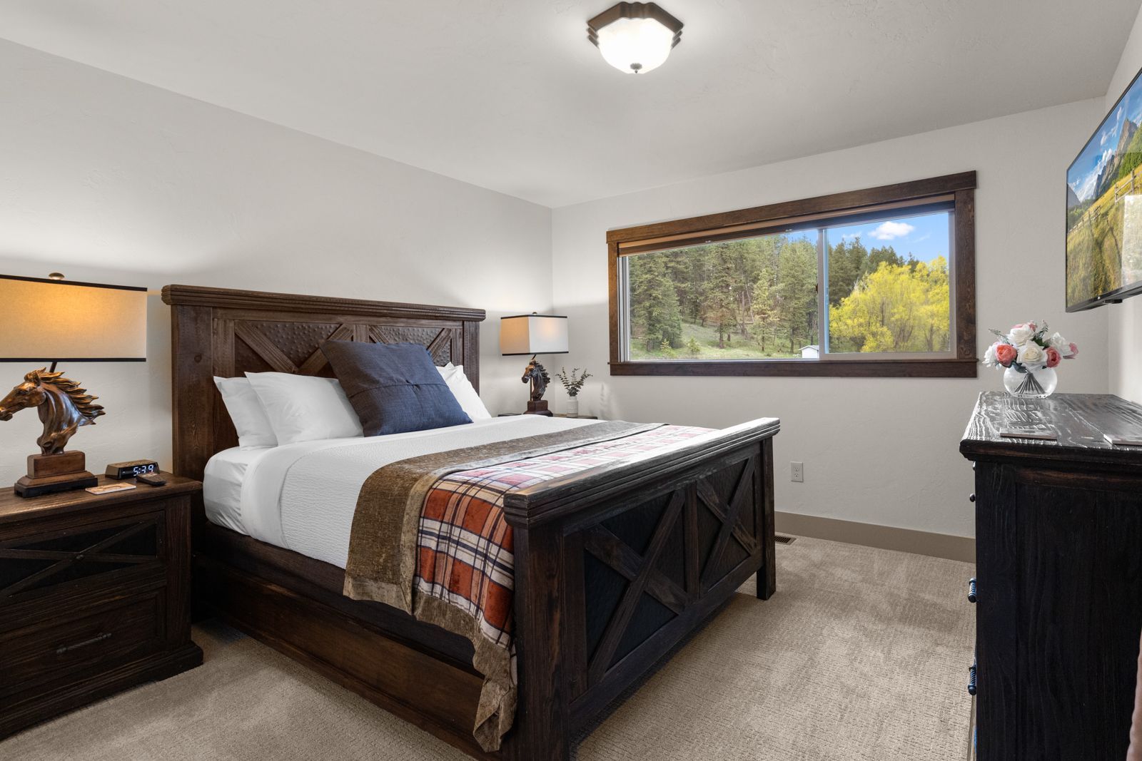 Cozy bedroom with a large wooden bed, nightstands, and a window overlooking trees