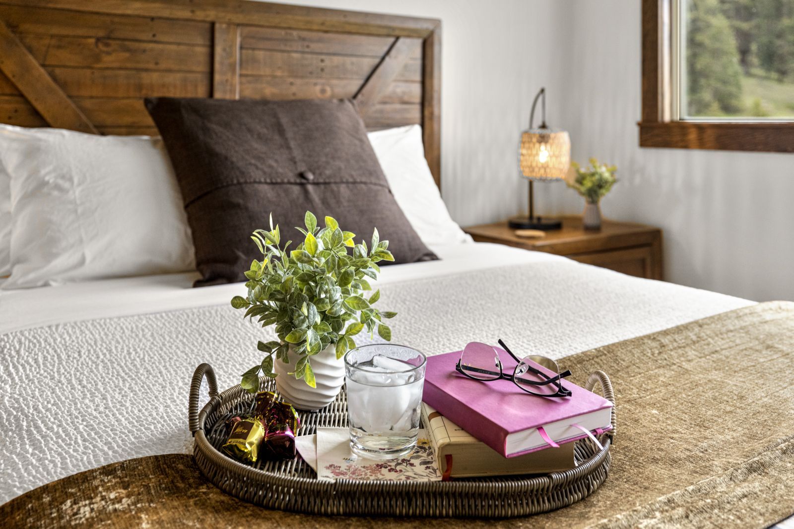 Bed with tray of flowers, tea, and a pink gift box on the blanket