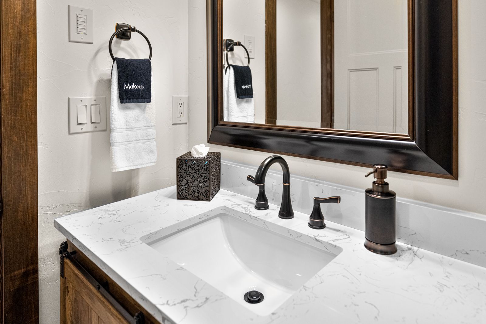 Modern bathroom vanity with white marble sink, black faucet, mirror, and towel ring.