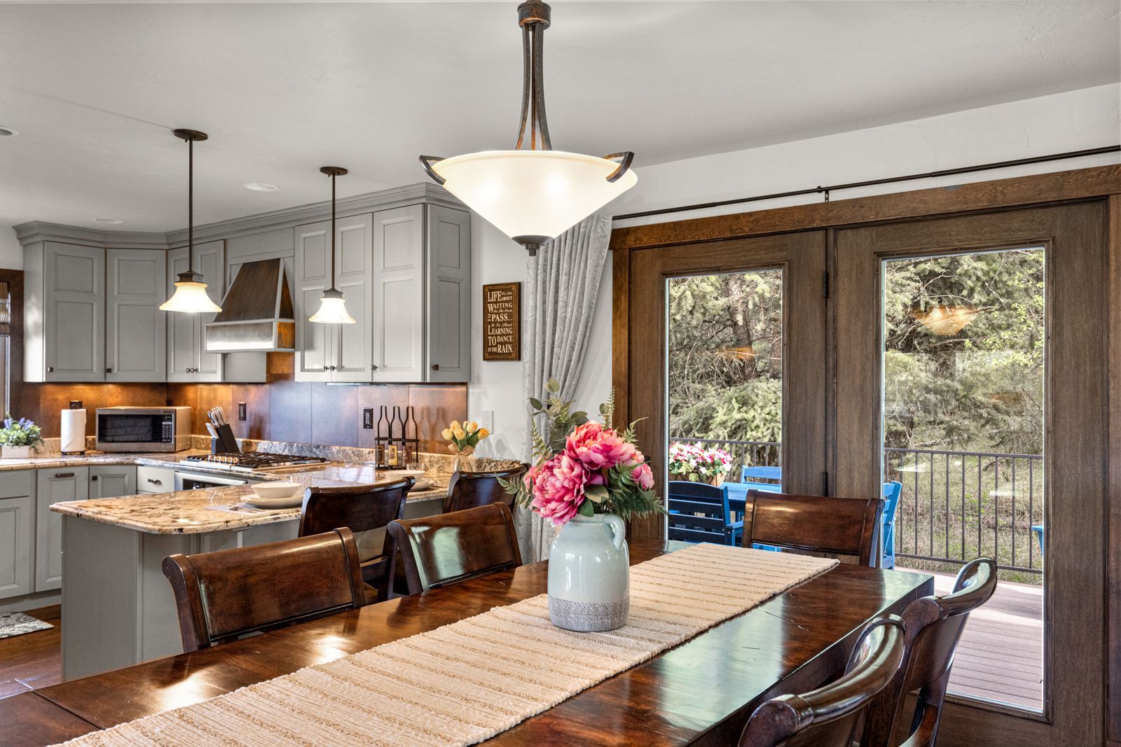 Bright open kitchen and dining area with island, pendant lights, and sliding doors to a deck
