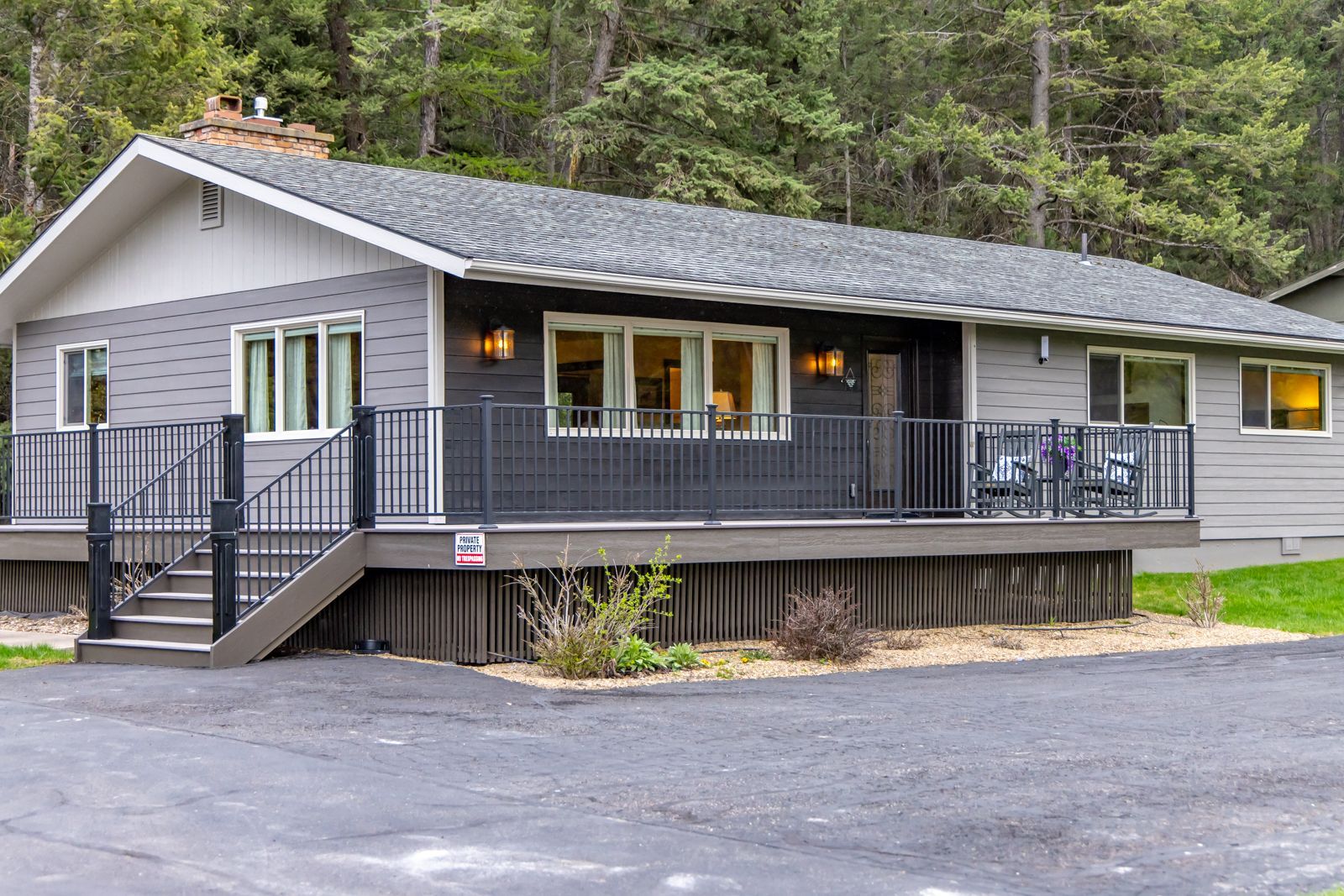 Gray cabin with deck and stairs in a wooded forest setting
