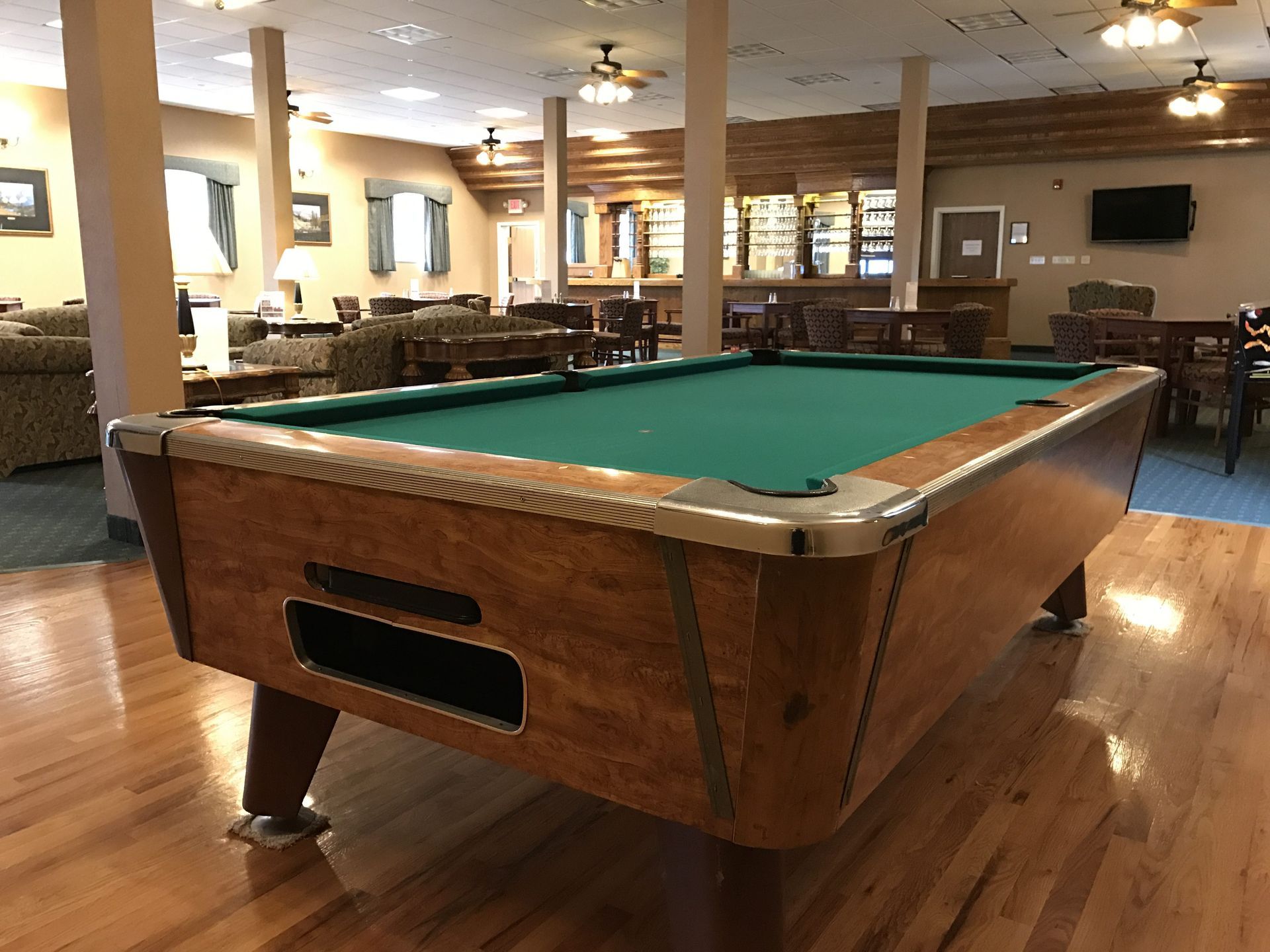 Pool table in a carpeted billiards room with wood floors and lounge seating