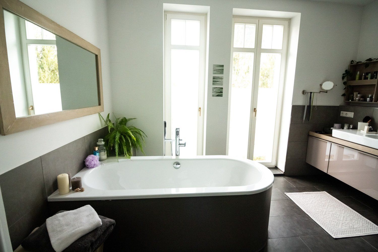 Bright modern bathroom remodeling in Arlington Heights, IL, featuring a freestanding tub, large mirror, and double vanity near French doors.