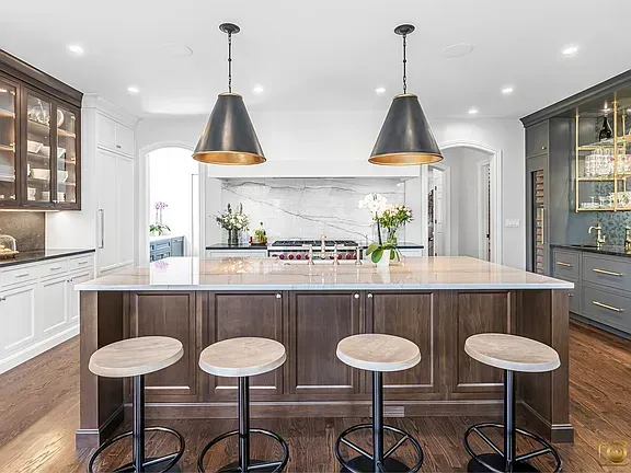 Modern kitchen remodeling with large island, four stools, black pendant lights, and white cabinets in Glenview, IL