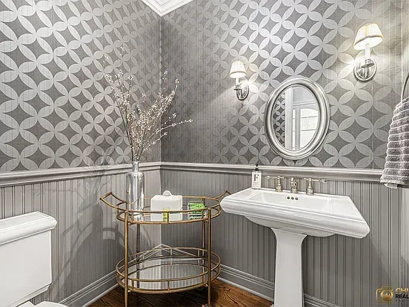 Elegant gray bathroom remodeling with wallpaper, wainscoting, gold cart, round mirror, and wall sconces in Glenview, IL.