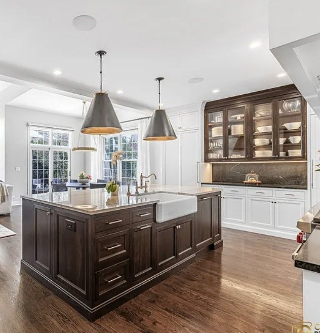 Bright modern kitchen remodeling with dark wood island, white cabinets, pendant lights, and glass-front hutch in Glenview
