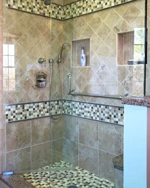 Tiled walk-in shower with corner shelf, grab bar, and mosaic border accents in a modern kitchen with gray cabinets, island, pendant lights, exposed wood beams, and two barstools in Arlington Heights, IL.