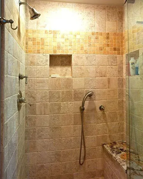 Small tiled shower stall with a handheld showerhead, wall niche, and glass partition. In a modern kitchen with gray cabinets, an island, pendant lights, exposed wood beams, and two barstools in Arlington Heights, IL.
