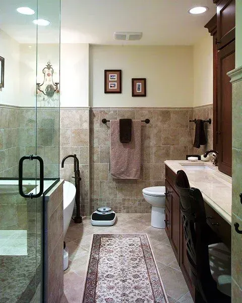 Bathroom with glass shower, vanity, toilet, rug, and towel racks in beige and green tones in Modern kitchen with gray cabinets, island, pendant lights, exposed wood beams, and two barstools in Arlington Heights, IL.