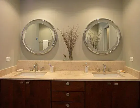 Bathroom vanity with double sinks, two round mirrors, and dark wood cabinets in a modern kitchen with gray cabinets, island, pendant lights, exposed wood beams, and two barstools in Arlington Heights, IL.