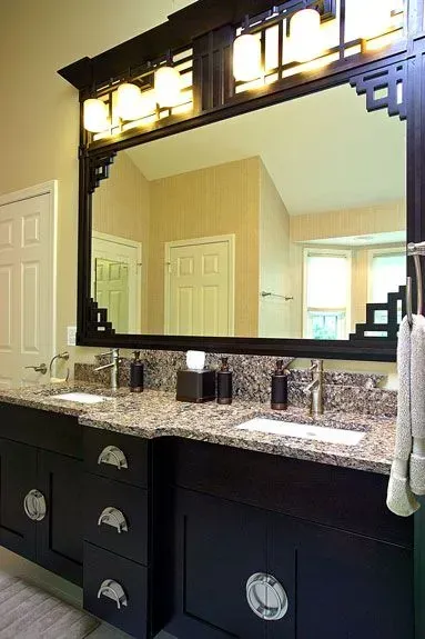 Bathroom vanity with black cabinets, granite countertop, and large framed mirror above sink. In Modern kitchen with gray cabinets, island, pendant lights, exposed wood beams, and two barstools in Arlington Heights, IL.