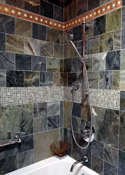 Tiled shower with dark green stone walls, mosaic accent strip, and handheld showerhead in a corner. In Modern kitchen with gray cabinets, island, pendant lights, exposed wood beams, and two barstools in Arlington Heights, IL.
