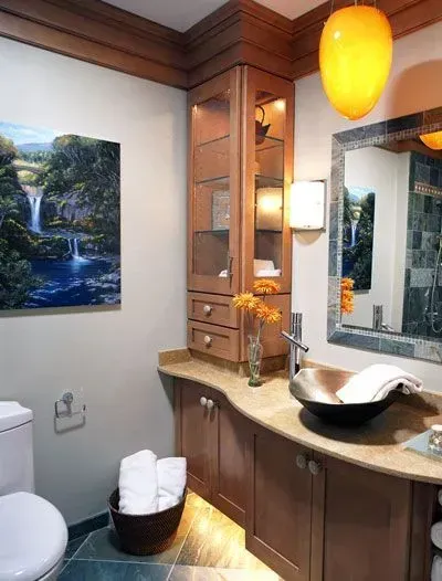 Modern bathroom with wood vanity, vessel sink, mirror, wall art, and warm pendant lighting. Modern kitchen with gray cabinets, island, pendant lights, exposed wood beams, and two barstools in Arlington Heights, IL.