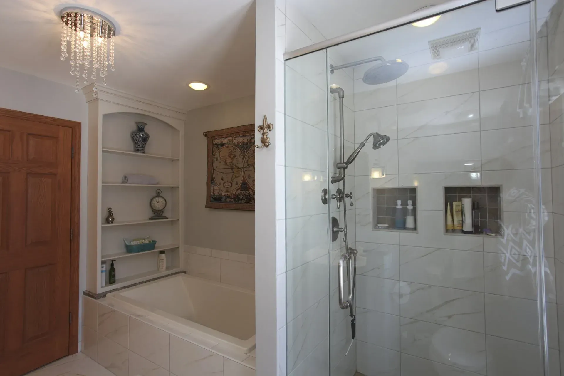 Bathroom with soaking tub, glass shower, and chandelier lighting with white tile walls in  Modern kitchen with gray cabinets, island, pendant lights, exposed wood beams, and two barstools in Arlington Heights, IL.