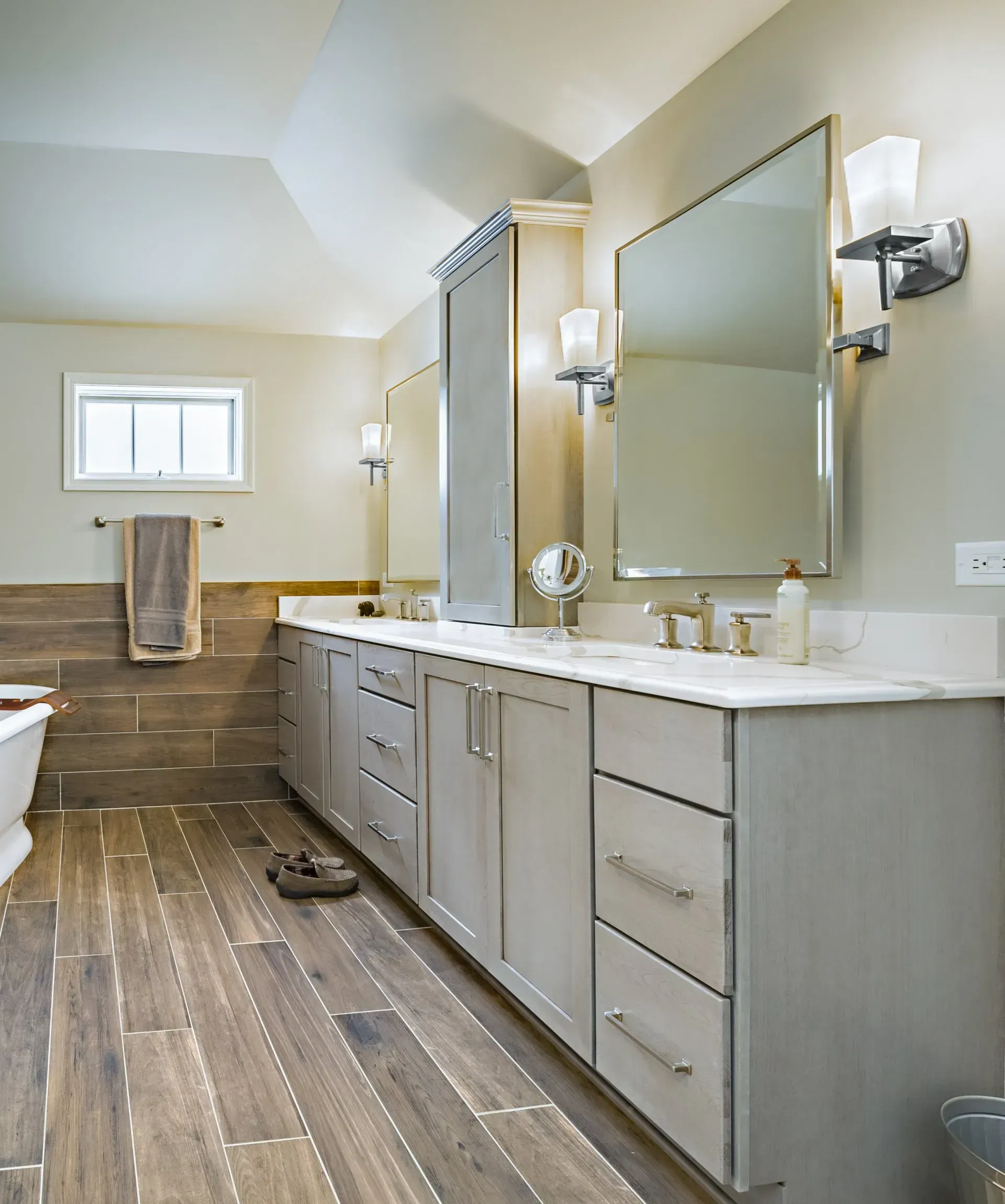 Modern bathroom with double vanity, large mirror, wall sconces, and wood-look floor in Modern kitchen with gray cabinets, island, pendant lights, exposed wood beams, and two barstools in Arlington Heights, IL.