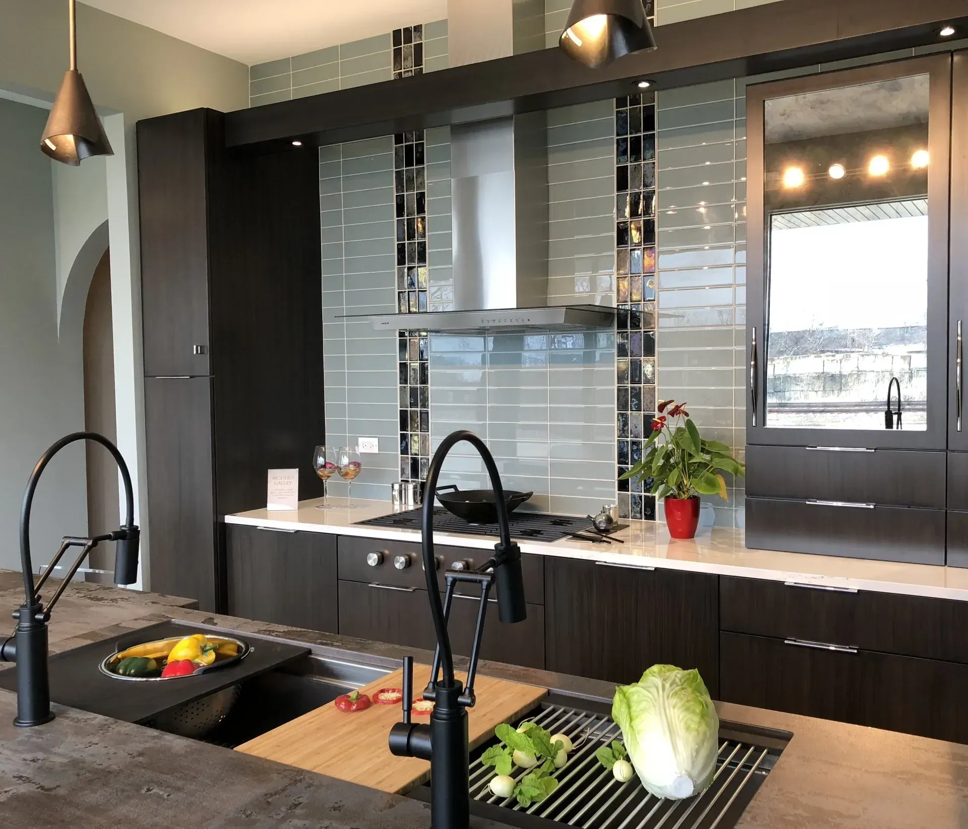 Modern kitchen remodeling with dark cabinets, island sink, and pendant lights, featuring a fruit bowl and vegetables in Arlington Heights, IL.