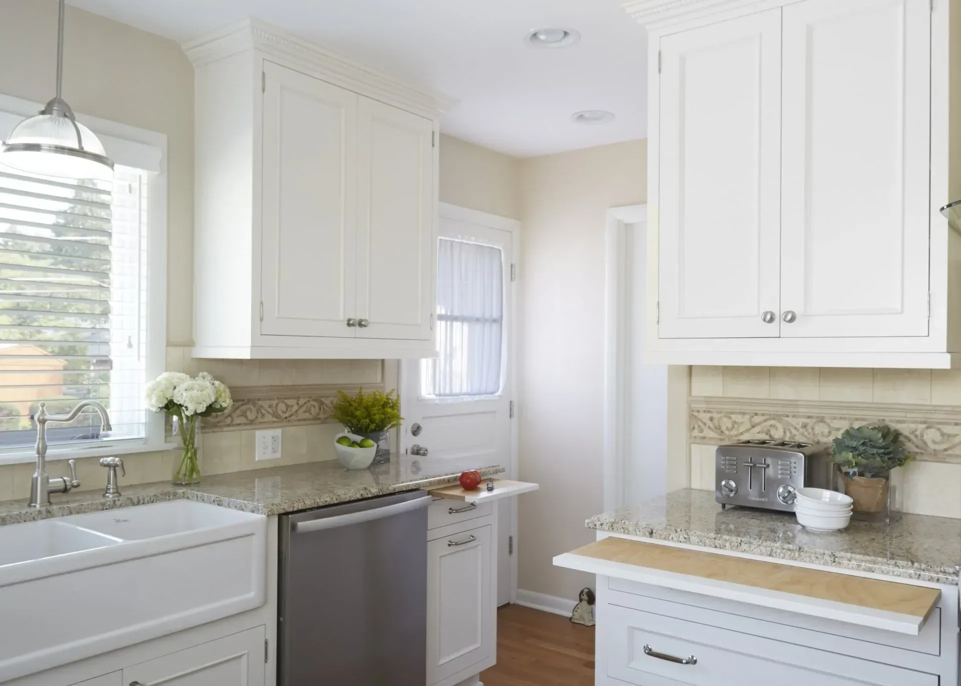 Bright white kitchen remodeling with cabinets, granite countertops, sink, and stainless dishwasher near a window in Kildeer, IL.