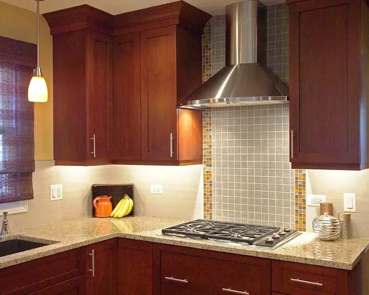 Modern kitchen remodeling with dark wood cabinets, stainless range hood, tiled backsplash, and beige countertops in Mount Prospect, IL 