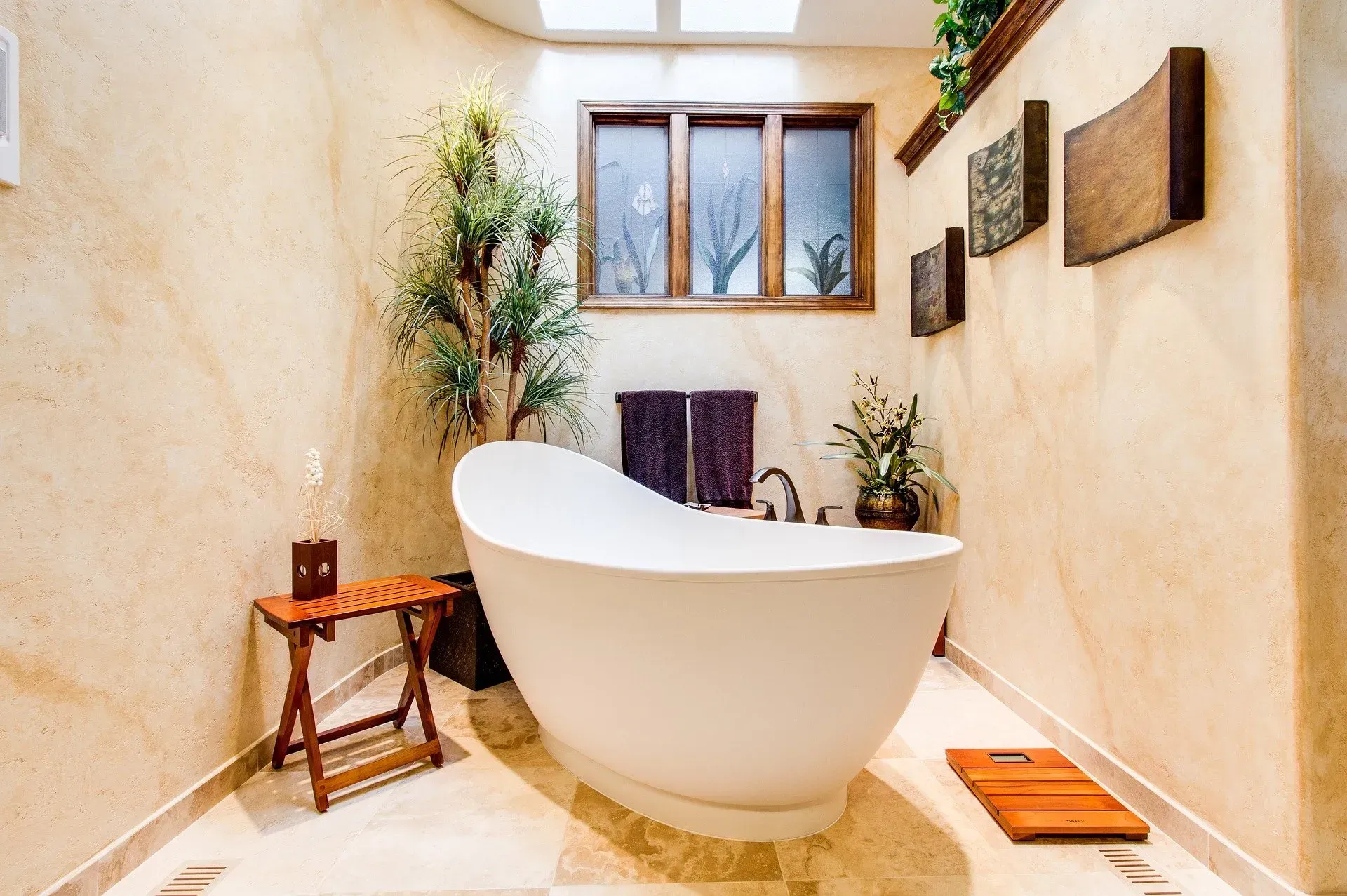 Modern bathroom remodeling with a freestanding white bathtub, window, plants, and warm beige walls in Palatine, IL