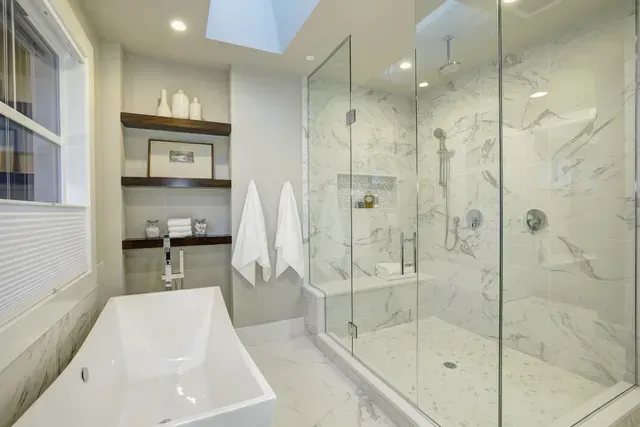 Modern bathroom with white tub, glass shower, and marble tile walls in Arlington Heights, IL.
