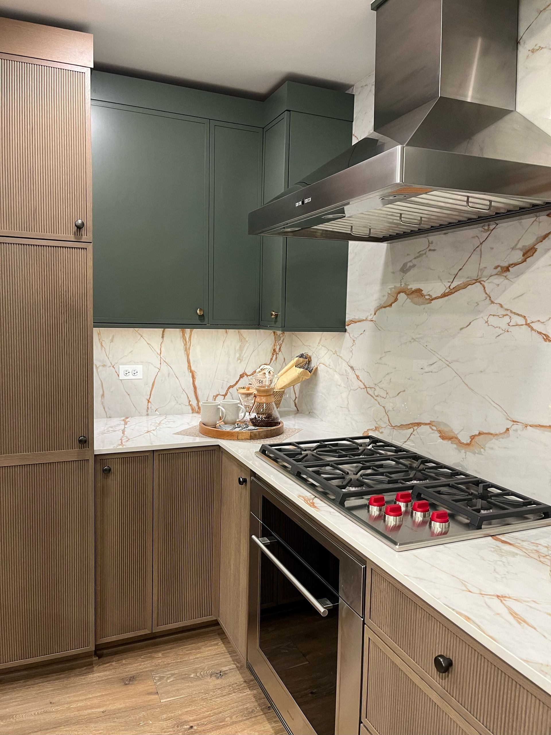 Our designers used a pairing of quarter-sawn oak and painted maple cabinets. The quartz countertop material runs all the way up the wall, replacing a more traditional tile backsplash.