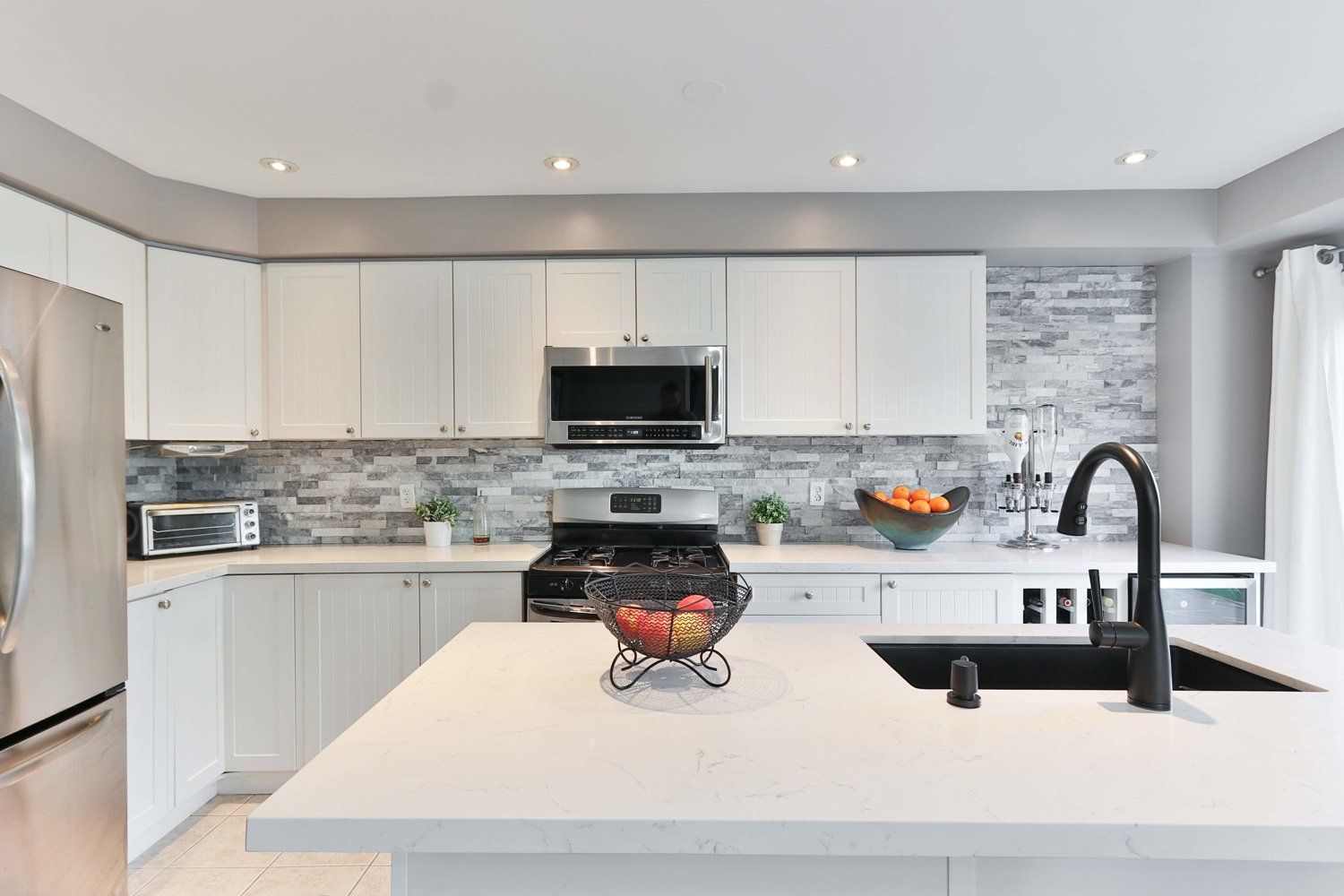 Bright modern kitchen with white cabinets, island, black faucet, and stainless steel appliances in Arlington Heights, IL