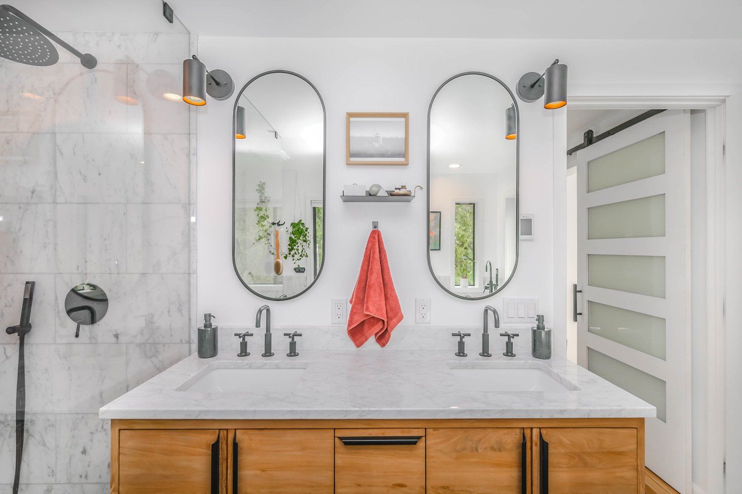 Bright bathroom vanity remodeling in Arlington Heights, IL, featuring twin oval mirrors, white marble countertops, and a coral hand towel.