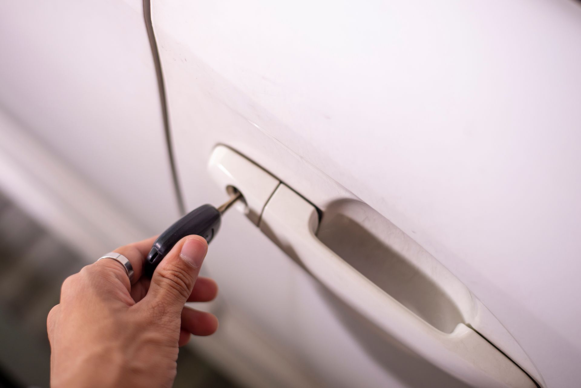 A man is using the key to unlock the car's door. A man is using the key to unlock the car's door.