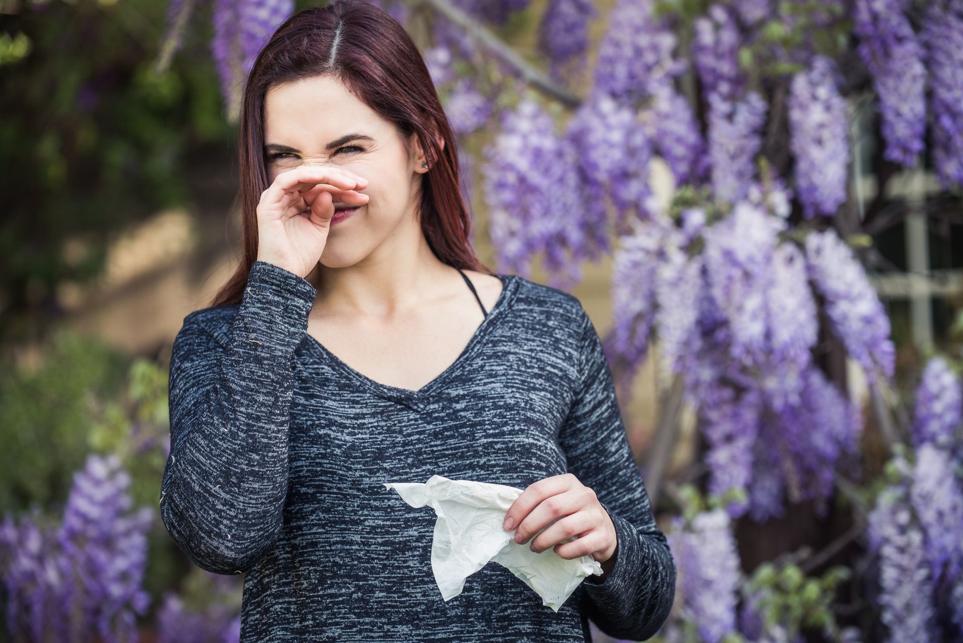 A Woman Blowing Her Nose In Front Of Purple Flowers | El Centro, CA | IV Termite & Pest Control Inc.